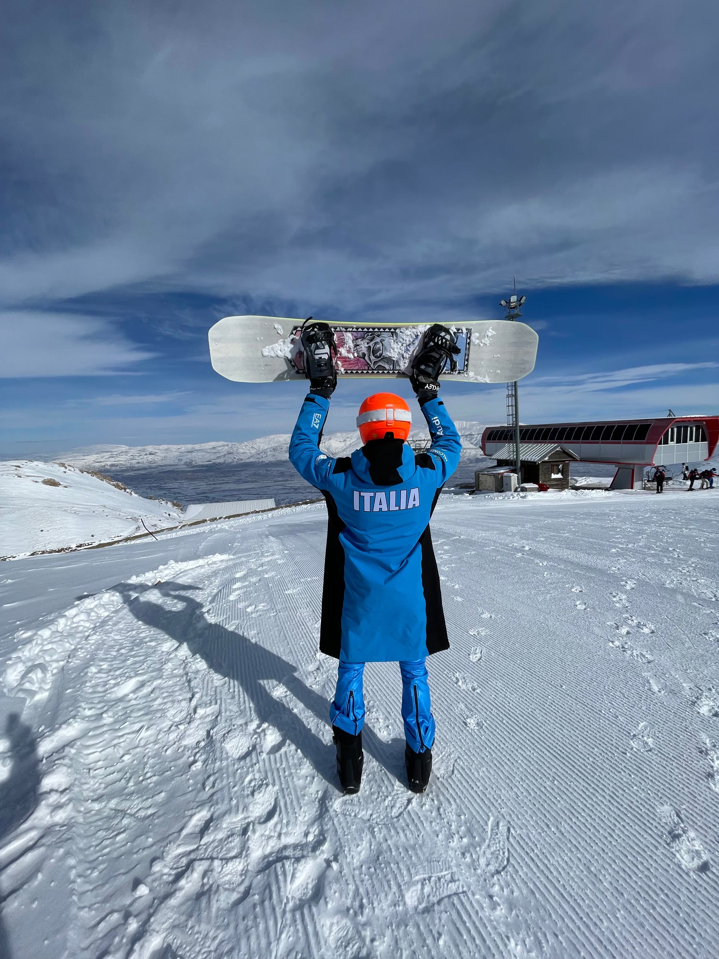 Octavian Buda in Italian national team kit, holding his snowboard on the mountain